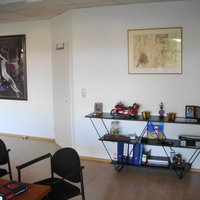 Innenraum mit einem Regal, zwei Bildern an den Wänden und einem Schreibtisch